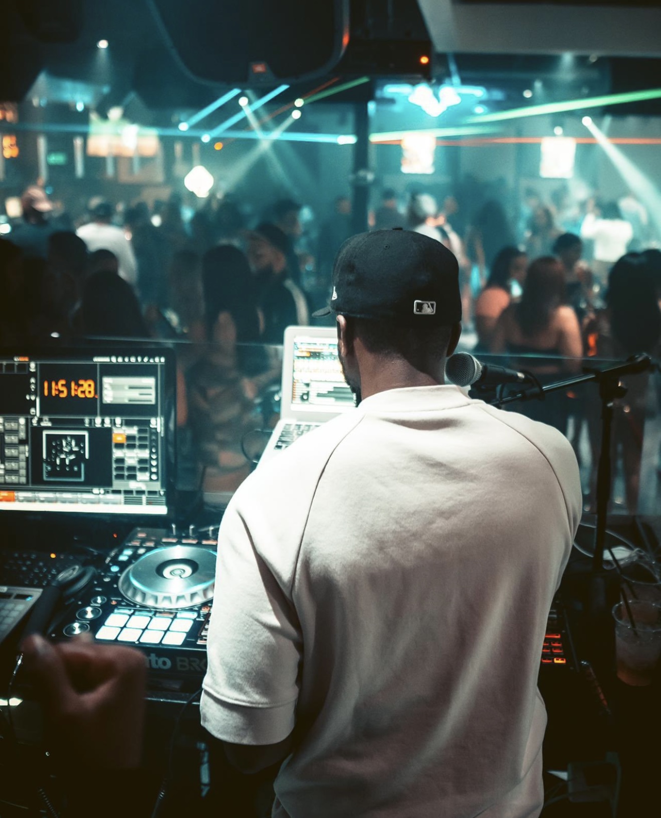 View from behind DJ Dutch overlooking the club crowd with green laser lights